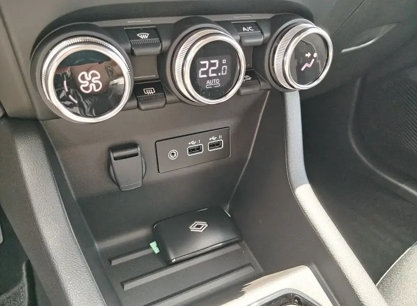 Vue rapprochée de la console centrale de la Renault Clio V TCE 90 Evolution 2026, avec commandes de climatisation et ports USB.