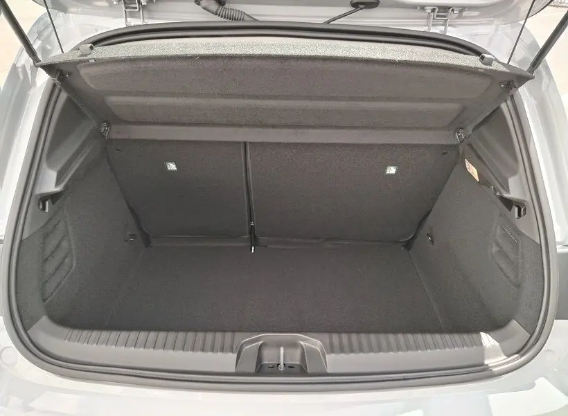 Coffre ouvert vu de l'arrière d'une Renault Clio V TCE 90 Evolution gris Rafale, montrant l'espace de chargement vide.