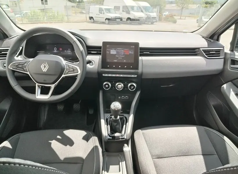 Vue intérieure avant de la Renault Clio V TCE 90 Evolution 2026, tableau de bord noir avec écran tactile et boîte manuelle.