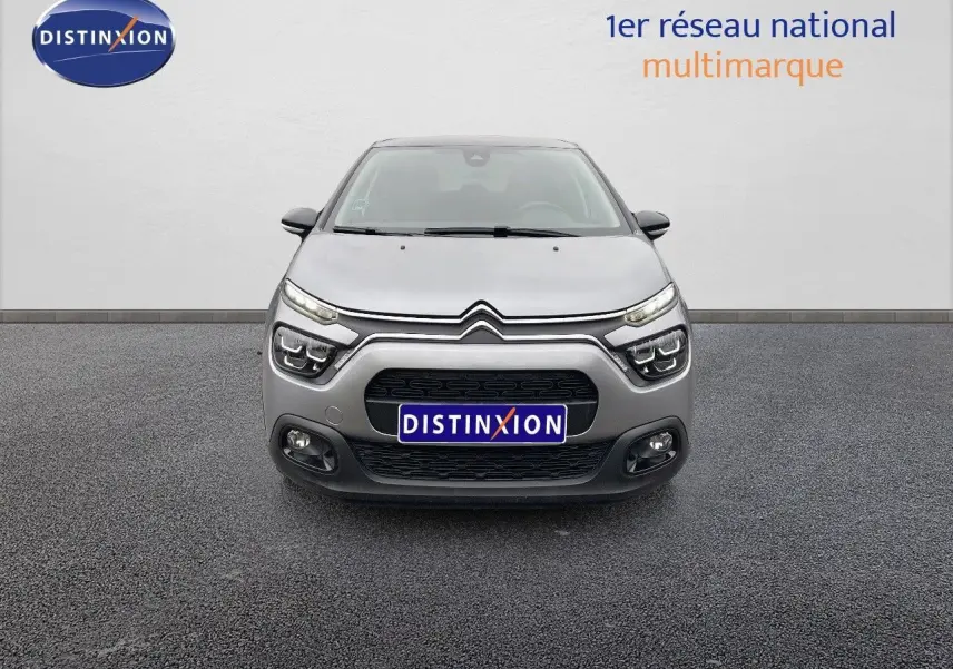 Vue frontale d'une Citroën C3 2023 gris acier métal avec toit noir, mettant en valeur ses phares LED et calandre distinctive.