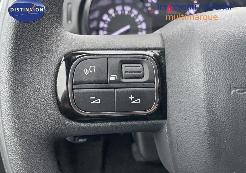 Gros plan sur les commandes de volume au volant d'une Citroën C3 gris acier avec toit noir, version Shine 2023.