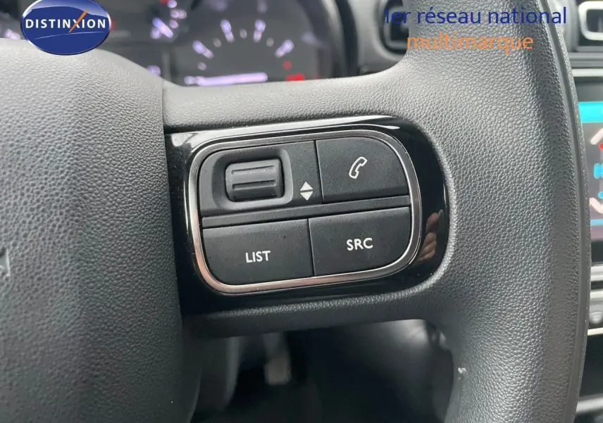 Gros plan sur les commandes gauche du volant en cuir noir de la Citroën C3 2023 gris acier métal avec toit noir.