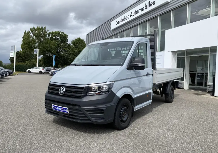 Volkswagen Crafter Fourgon gris argent vu en 3/4 avant droit avec plateau ridelles et calandre noire.
