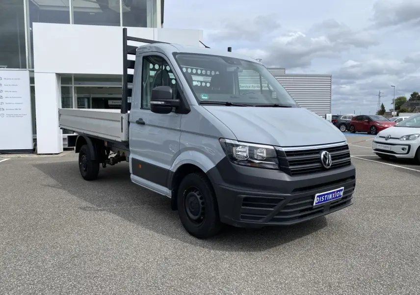 Volkswagen Crafter Fourgon gris argent vu en 3/4 avant droit avec plateau et ridelles aluminium rabattables.