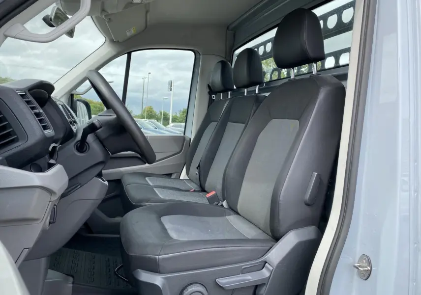 Vue intérieure côté conducteur du Volkswagen Crafter Business Line 2020 avec sellerie tissu gris et tableau de bord noir.