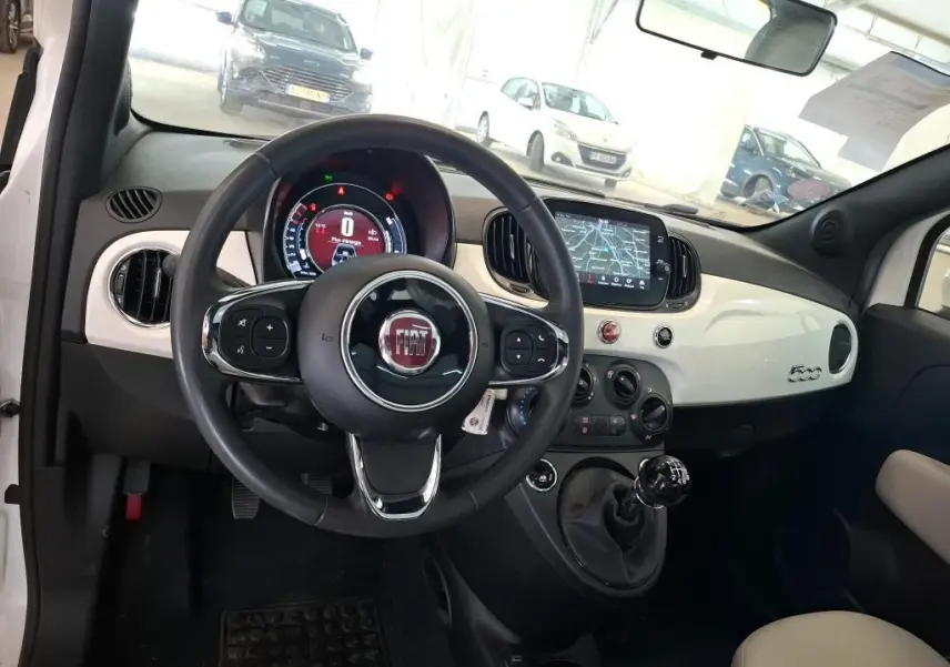 Vue intérieure du tableau de bord blanc et volant de la Fiat 500 DolceVita Plus 2022 avec boîte manuelle et écran tactile.