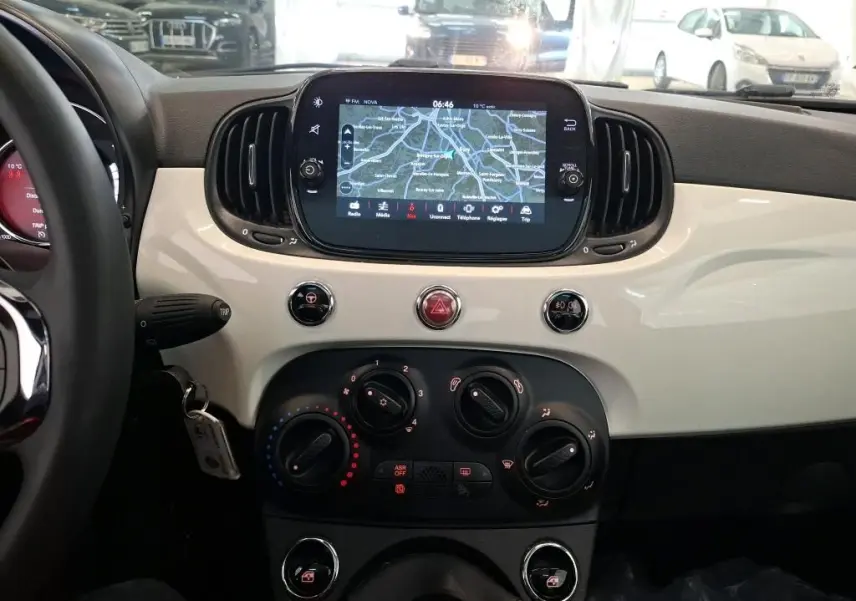 Vue intérieure du tableau de bord blanc brillant d'une Fiat 500 DolceVita Plus 2022 avec écran tactile et commandes manuelles.