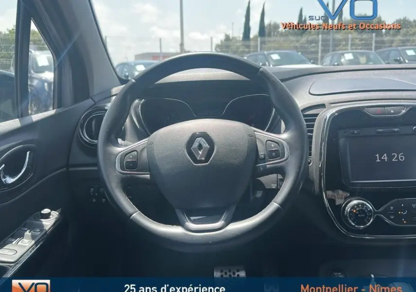 Vue centrée sur le volant cuir et tableau de bord du Renault Captur gris clair, avec écran tactile et commandes au volant visibles.