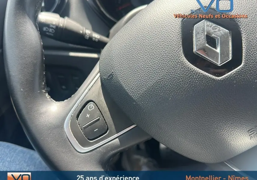 Gros plan sur le volant cuir du Renault Captur gris clair, montrant les commandes de régulateur de vitesse à gauche.