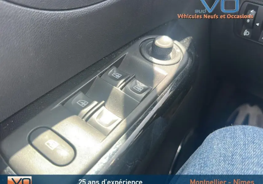 Gros plan sur les commandes électriques des vitres et réglage des rétroviseurs côté conducteur d'un Renault Captur gris clair.