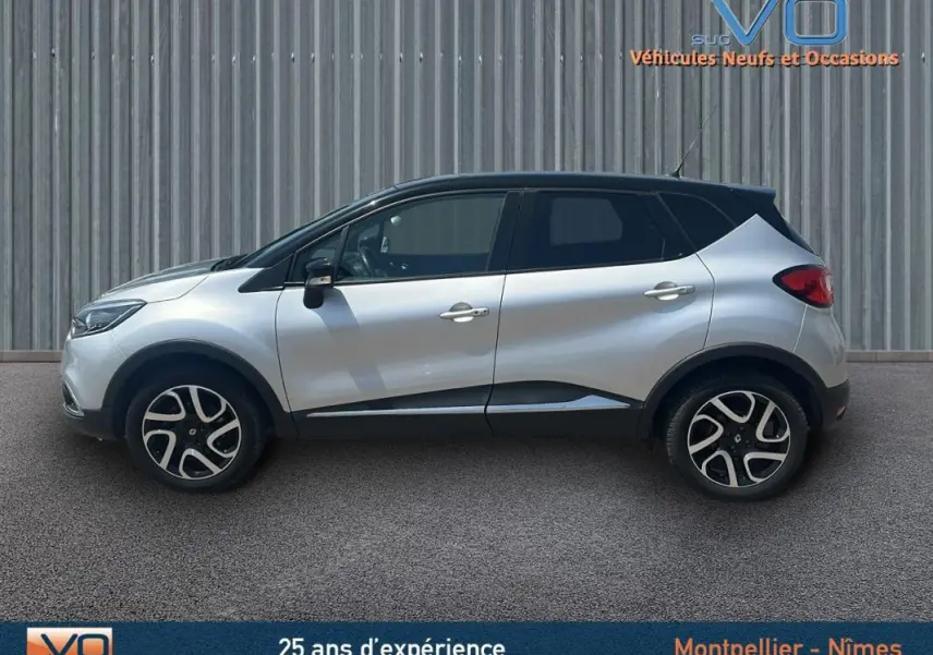 Profil côté gauche d'un Renault Captur gris clair 2016 avec jantes alliage et toit noir sur fond industriel.