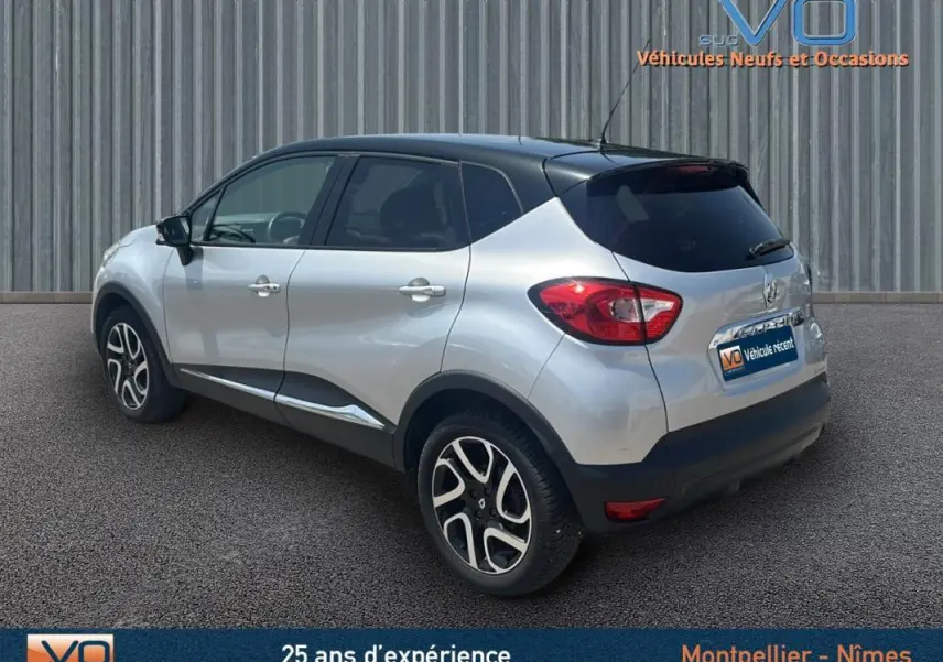 Vue 3/4 arrière droite d'un Renault Captur gris clair avec toit noir et jantes alliage 16 pouces sur sol goudronné.