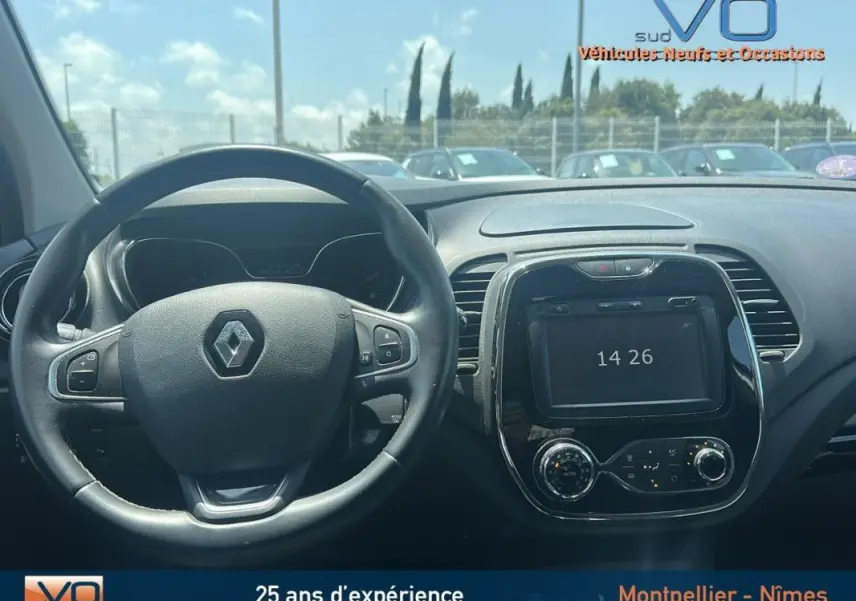 Vue intérieure du tableau de bord du Renault Captur gris clair 2016 avec volant cuir et écran tactile central.