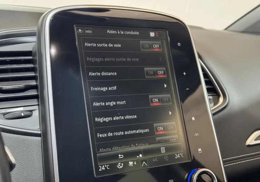 Gros plan sur l'écran tactile central du tableau de bord du Renault Scénic Intens rouge 2021 affichant les aides à la conduite.