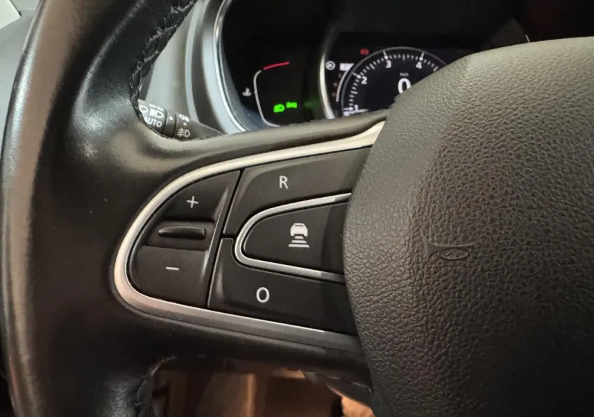 Gros plan sur les commandes du volant cuir noir du Renault Scénic Intens 2021, avec tableau de bord numérique en arrière-plan.