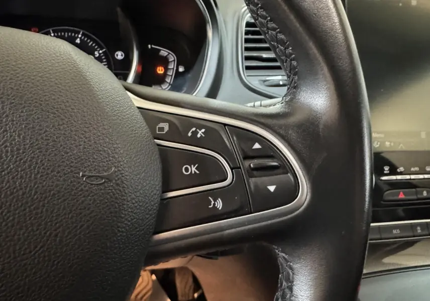Gros plan sur le volant cuir noir côté gauche du Renault Scénic Intens TCe 160 EDC 2021 avec commandes intégrées.