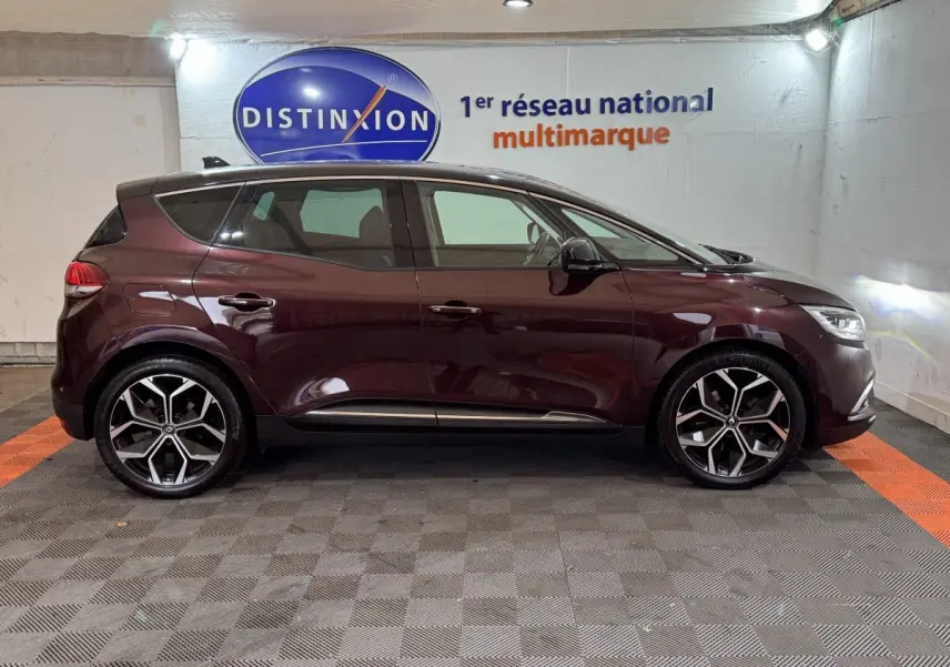 Profil droit d'un Renault Scénic Intens rouge foncé 2021 avec jantes alliage et vitres teintées en intérieur showroom.