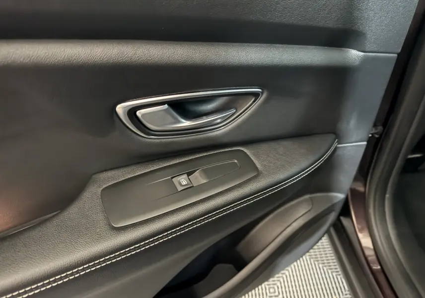 Poignée intérieure et commande de lève-vitre sur la porte avant droite en cuir noir avec surpiqûres blanches du Renault Scénic Intens rouge 2021.