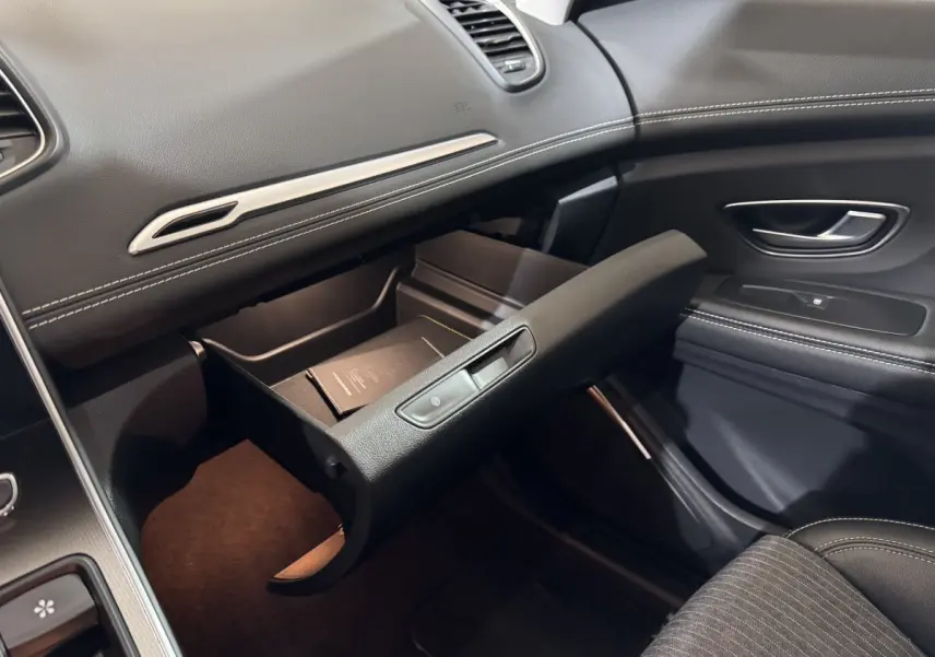 Intérieur noir du Renault Scénic Intens 2021, vue côté passager avec boîte à gants ouverte et détails coutures blanches.