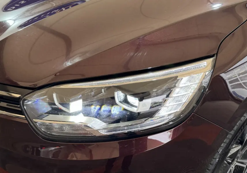 Gros plan sur le phare avant droit LED du Renault Scénic Intens rouge foncé 2021, soulignant ses détails modernes.
