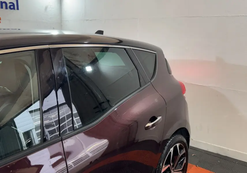 Vue côté arrière droit du Renault Scénic Intens TCe 160 rouge, mettant en valeur la porte et la jante au design moderne.