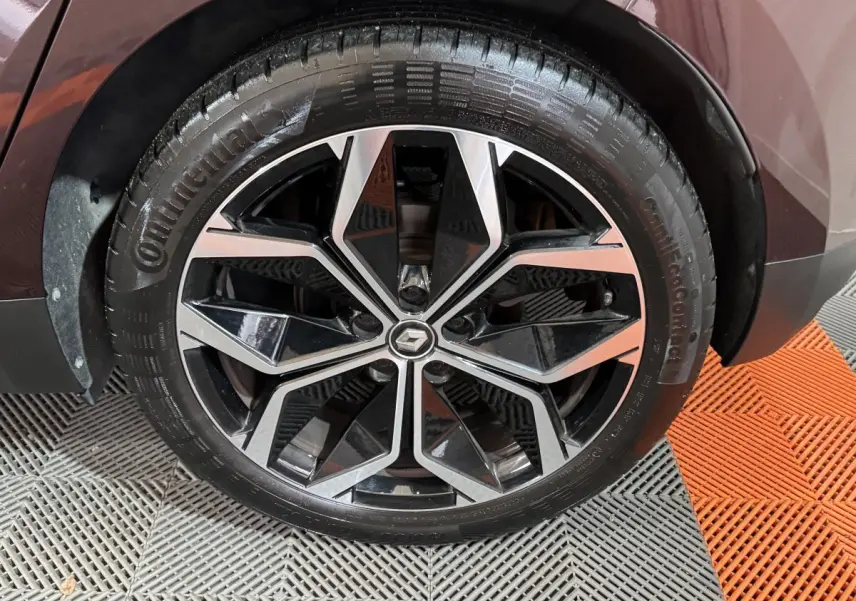 Gros plan sur la roue avant droite du Renault Scénic Intens rouge 2021 avec jante alliage noire et argentée.