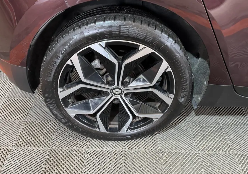 Gros plan sur la roue arrière droite rouge d’un Renault Scénic Intens 2021 avec jante alliage noire et argentée.