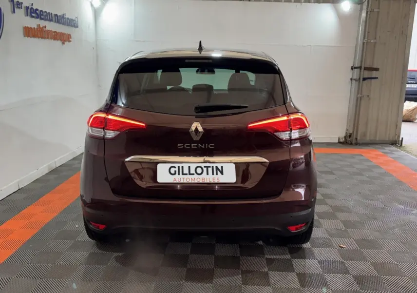 Vue arrière d'un Renault Scénic rouge foncé avec feux LED allumés, stationné dans un garage intérieur.