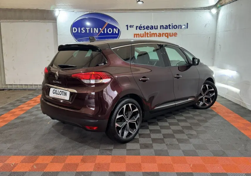 Renault Scénic rouge foncé vue 3/4 arrière droit en intérieur avec jantes alliage et vitres teintées.