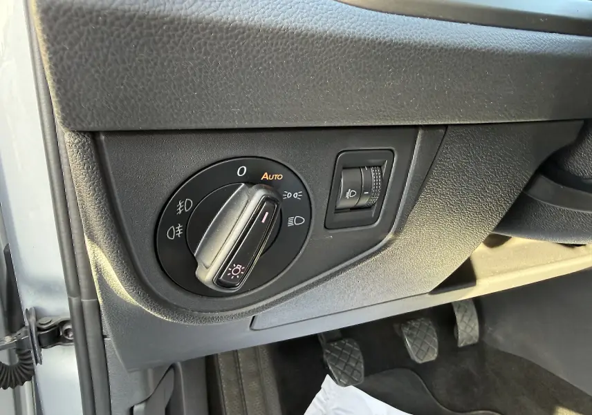 Gros plan sur le bouton de commande des phares noir dans l'habitacle gris d'une Volkswagen Polo 1.0 TSI 95 Lounge Business 2021.