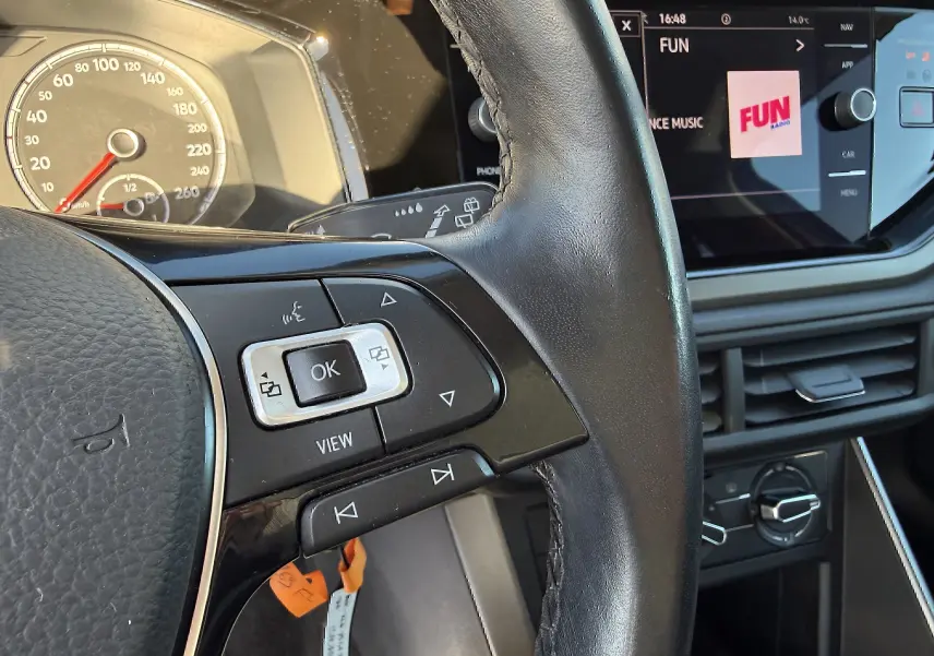 Vue rapprochée du volant et du tableau de bord d’une Volkswagen Polo gris métal 2021 avec commandes au volant et écran tactile.