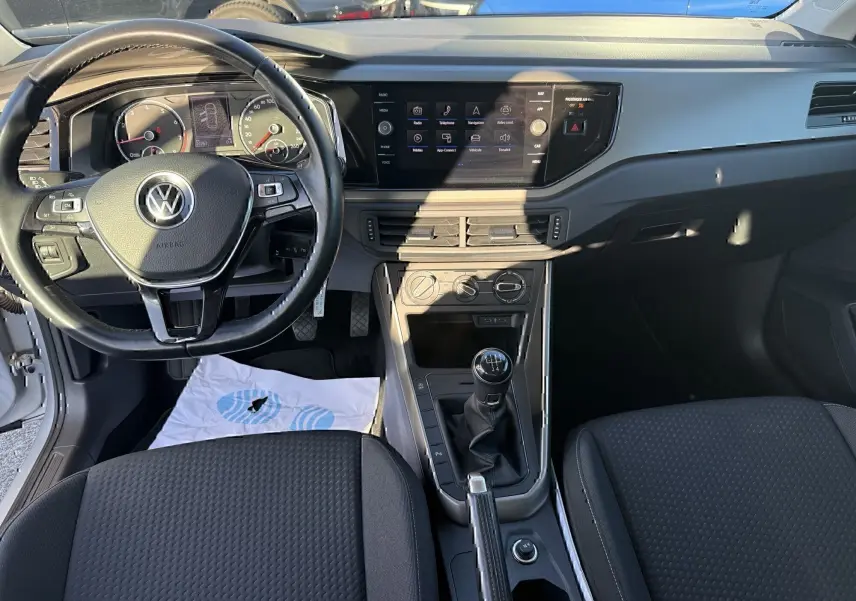Vue intérieure avant de la Volkswagen Polo 1.0 TSI 95 Lounge Business 2021, montrant le volant, tableau de bord et levier de vitesses manuel.