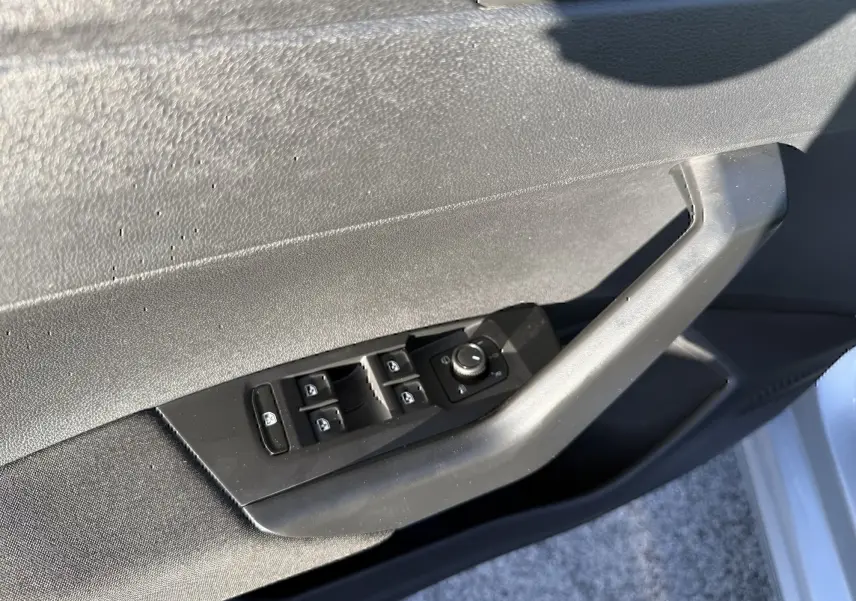Détail des commandes de lève-vitres et rétroviseurs sur la porte côté gauche d’une Volkswagen Polo gris métal 2021.