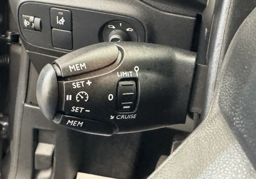 Gros plan sur la commande de régulateur de vitesse côté gauche du volant d'une Citroën C3 gris foncé de 2020.