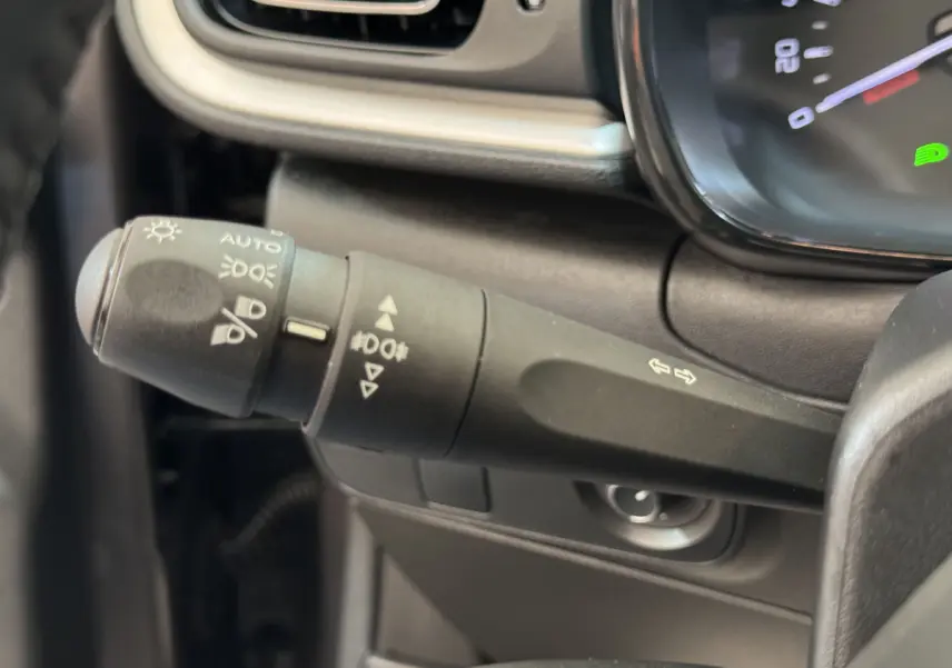 Gros plan sur la manette de commande des phares et clignotants dans l’habitacle d’une Citroën C3 2020 gris foncé.