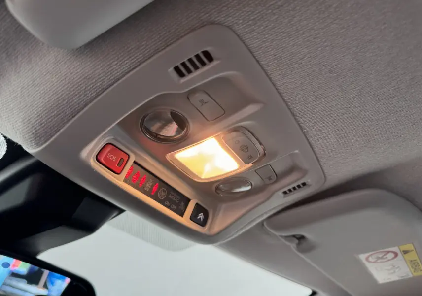 Vue intérieure en contre-plongée du plafonnier gris clair avec éclairage et boutons de commande dans une Citroën C3 gris foncé.
