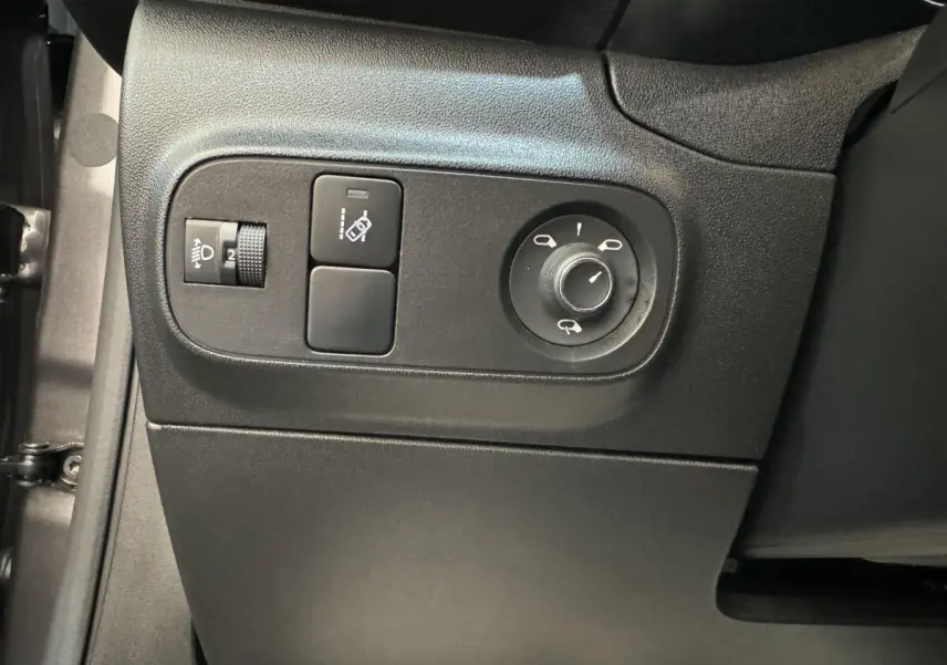 Vue rapprochée des commandes de réglage des rétroviseurs et des phares sur le côté gauche intérieur d'une Citroën C3 gris foncé.