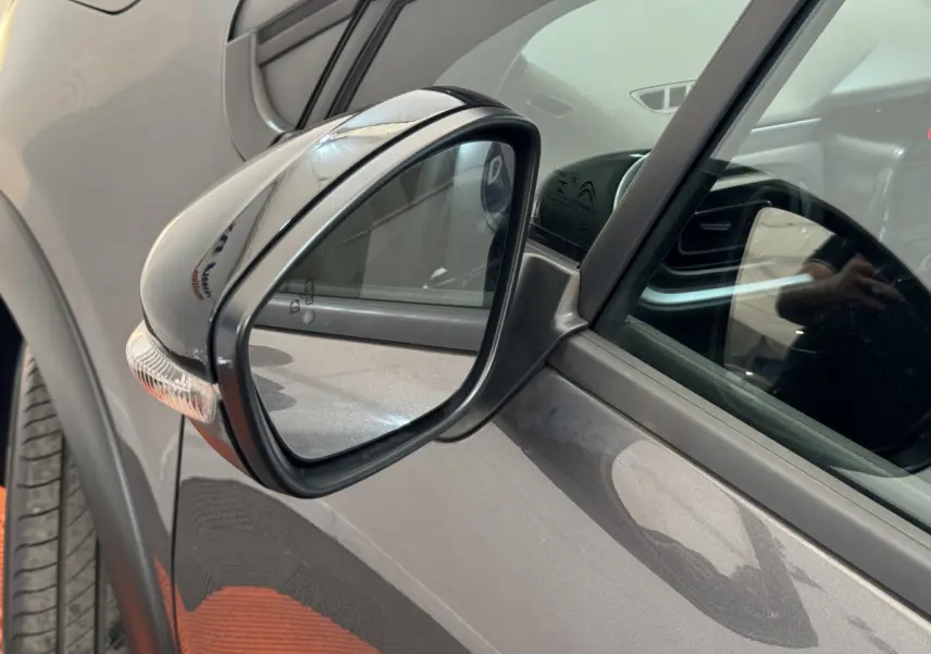 Rétroviseur côté conducteur d'une Citroën C3 gris foncé, avec clignotant intégré, vue rapprochée.