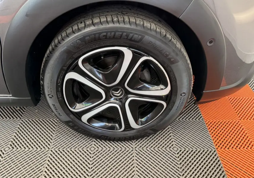 Gros plan sur la roue avant droite d’une Citroën C3 gris foncé, avec jante noire et argentée au design moderne.