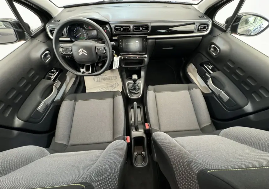 Vue intérieure avant de la Citroën C3 2020, tableau de bord noir brillant avec écran tactile et sièges tissu gris clair.