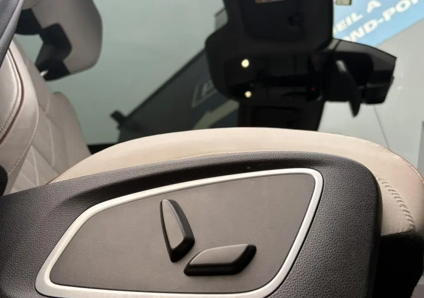 Détail des commandes de réglage électrique du siège avant en cuir gris sable clair dans un Renault Espace VI.