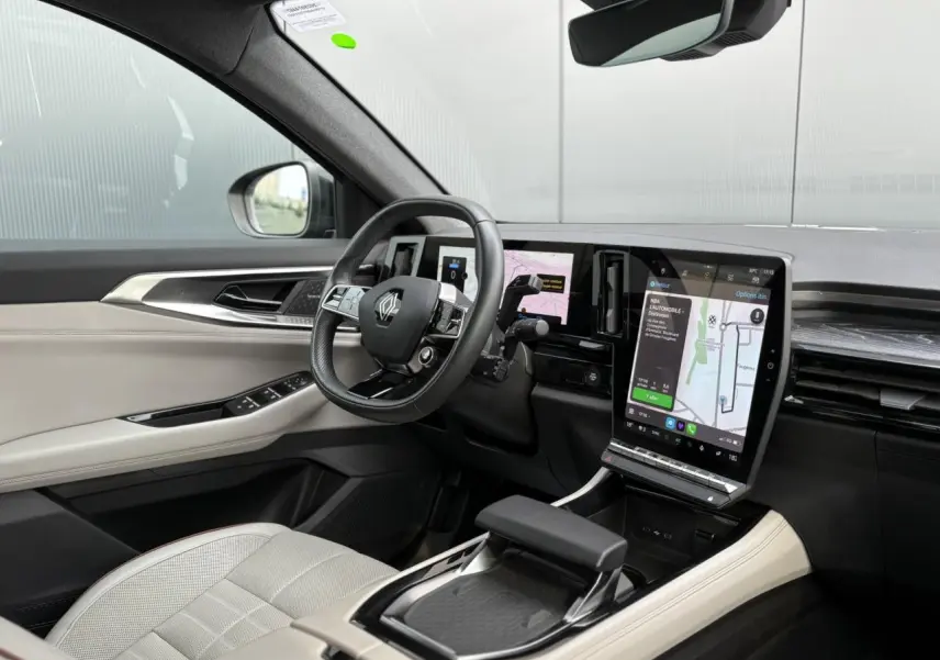 Intérieur avant droit du Renault Espace VI hybride, sellerie cuir sable clair et écran tactile vertical lumineux.