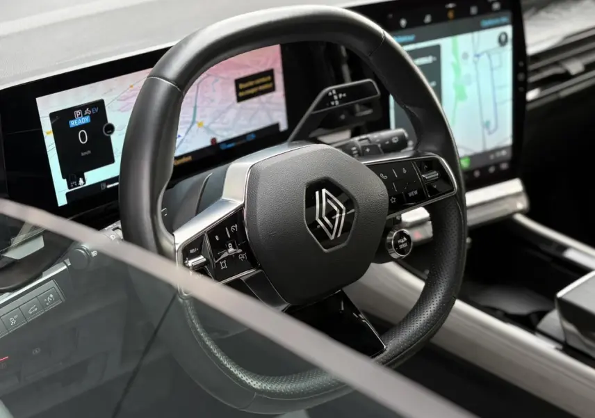 Vue rapprochée du volant cuir noir du Renault Espace VI 6 E-Tech avec tableau de bord numérique et écran tactile central.