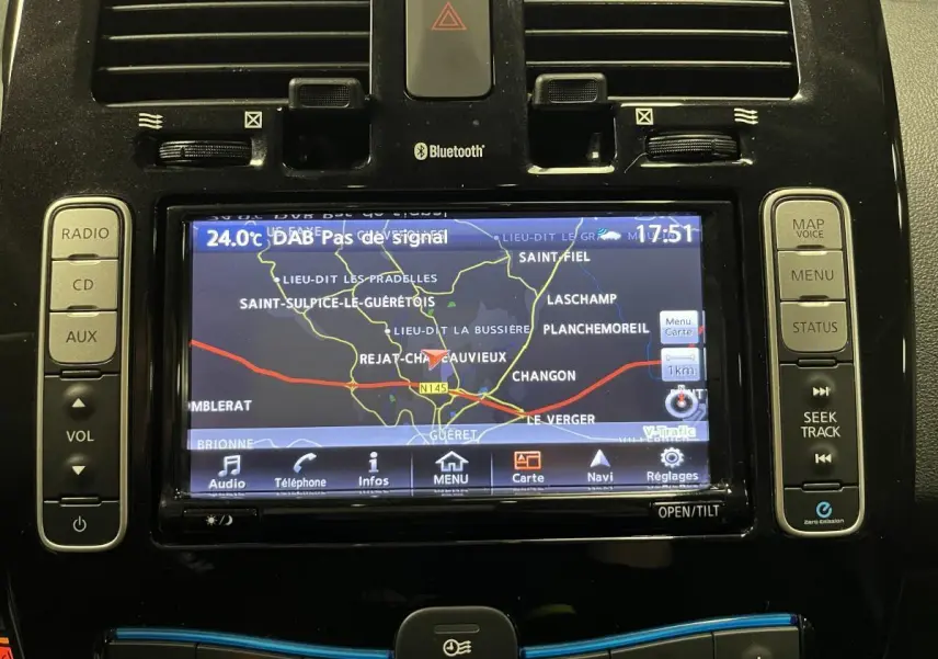 Écran tactile central du tableau de bord de la Nissan Leaf rouge 2017 affichant la navigation GPS et commandes audio.