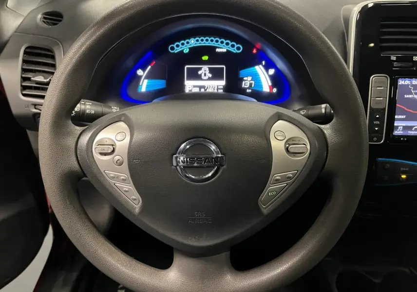 Vue rapprochée du volant Nissan Leaf 2017 avec commandes intégrées et tableau de bord numérique éclairé en bleu.