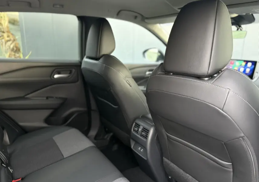 Vue intérieure arrière du Nissan Qashqai III gris Ceramic, sièges en cuir noir et tissu, avec aérateurs centraux et ports USB.