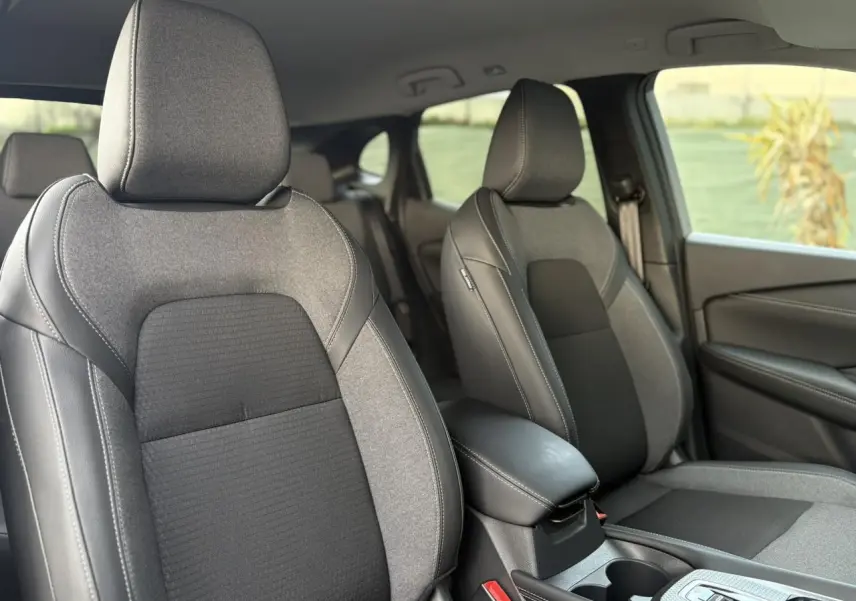 Vue intérieure rapprochée des sièges avant gris et noirs du Nissan Qashqai III e-Power 2025, avec accoudoir central visible.