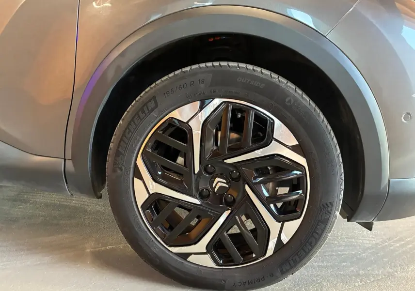 Gros plan sur la roue avant droite d’une Citroën C4 X gris, avec jante alliage bicolore et pneu Michelin.