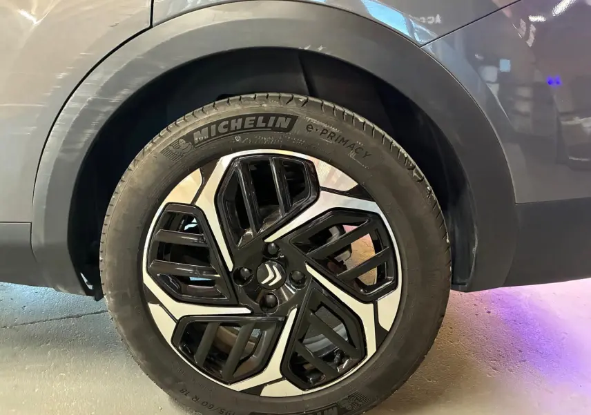 Gros plan sur la roue avant droite d'une Citroën C4 X gris 2024 avec jante alliage noire et argentée distinctive.