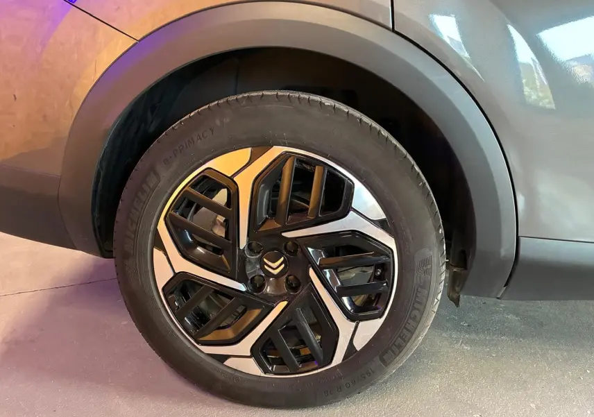 Gros plan sur la roue avant droite d'une Citroën C4 X gris 2024, mettant en valeur la jante noire et argentée au design géométrique.